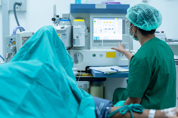 assistent op zoek hartslagmeter chirurg team in uniform voert een operatie uit op een patiënt in een hartchirurgie kliniek. Moderne geneeskunde, een professioneel team van chirurgen, gezondheid. - Foto, afbeelding