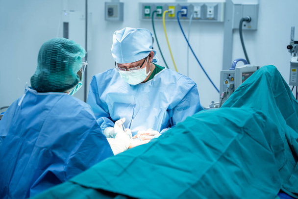 Cirurgiões e um assistente Mãos para fora Instrumentos que operam o osso no braço do paciente na sala de cirurgia. Médicos Profissionais Realizando Cirurgia, conceito de cirurgião ortopédico - Foto, Imagem