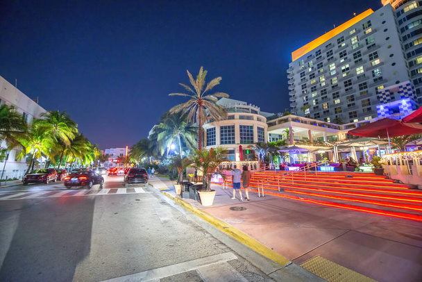 Una strada con palme ed edifici di notte, Mia Beach Ocean Boulevard. - Foto, immagini