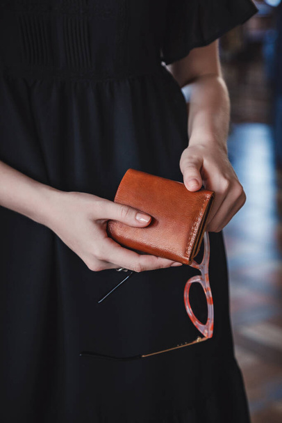 The woman is holding a brown leather wallet - Фото, зображення