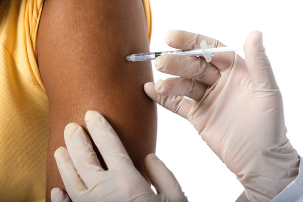 Ausgeschnittene Ansicht eines Arztes in Latexhandschuhen bei der Impfung eines Afroamerikaners isoliert auf weißem Grund  - Foto, Bild