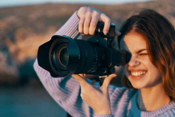 gelukkig vrouw fotograaf met camera in bergen op de natuur en rivier op de achtergrond - Foto, afbeelding