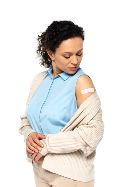 Africano americano mulher olhando para adesivo gesso no braço isolado no branco  - Foto, Imagem