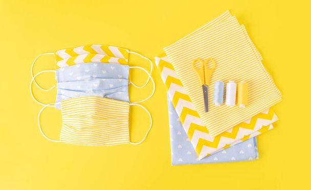 Eco-friendly reusable cloth face shield and sewing accessories on top yellow background. Homemade breathing mask making, - Photo, Image