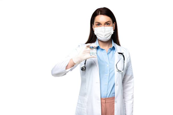 Brunette doctor in medical mask holding jars with vaccine isolated on white  - Foto, immagini