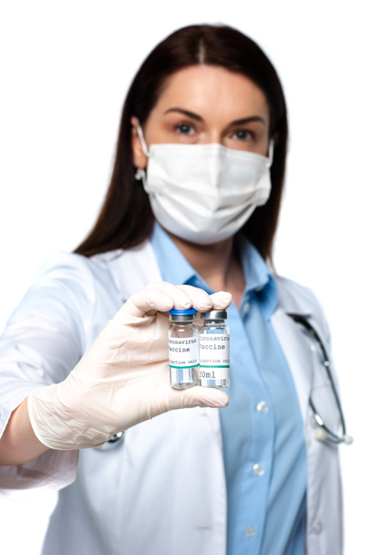 Blurred doctor in medical mask holding jars with vaccine isolated on white  - Fotografie, Obrázek