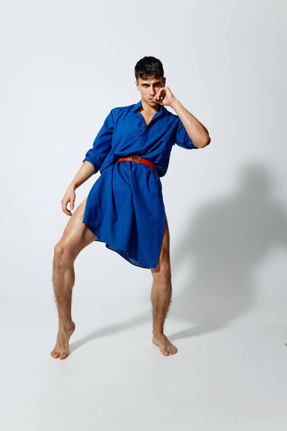 a man in a blue dress with a red belt in full growth on a light background  - Foto, immagini