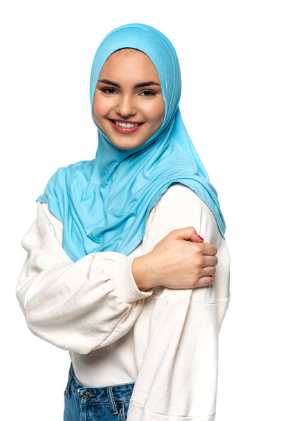 Smiling arabian woman in blue hijab looking at camera isolated on white  - 写真・画像