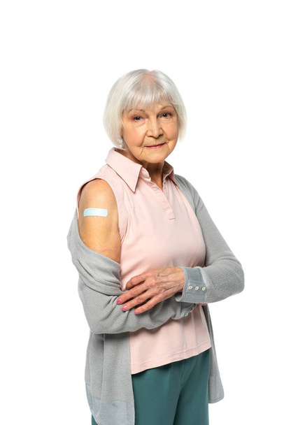 Elderly woman with adhesive patch on arm looking at camera isolated on white  - Fotografie, Obrázek