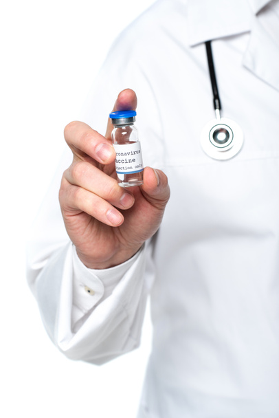Vista recortada del frasco con la vacuna contra el coronavirus en la mano del médico desenfocado aislado en blanco  - Foto, Imagen