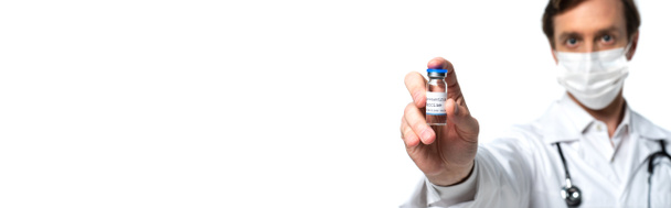 Szczepionka koronawirusowa w ręku poparzonego lekarza w masce ochronnej izolowanej na białym, banerowym banerze  - Zdjęcie, obraz