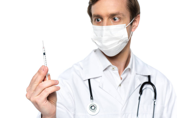 白で隔離された背景にぼやけた背景に医療用マスクで医師の手にワクチンで注射  - 写真・画像