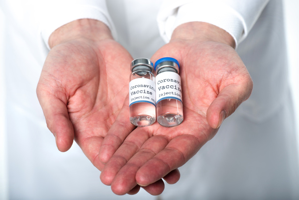 Vue en culture du vaccin contre le coronavirus entre les mains d'un médecin isolé sur du blanc  - Photo, image
