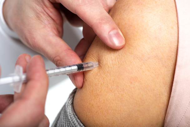 Nahaufnahme des Arztes bei der Injektion von Impfstoff an ältere Frau isoliert auf weiß  - Foto, Bild