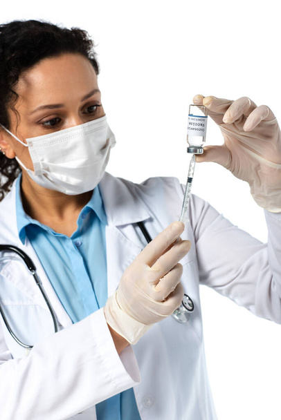 Vacina contra o coronavírus e seringa nas mãos de um médico afro-americano desfocado, isolado no branco  - Foto, Imagem
