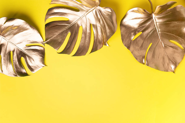 Floral minimal style concept. Exotic summer trend. Golden tropical palm monstera leaf on yellow color background. Shiny and sparkle design, fashion concept. - Fotoğraf, Görsel