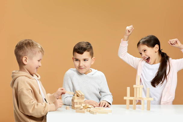 children plays with wooden constructor on desk. - Foto, afbeelding