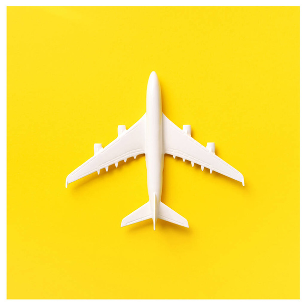 Travel, vacation concept. White model airplane on yellow color background with copy space. Top view. Flat lay. Minimal style design. Square crop - Фото, изображение