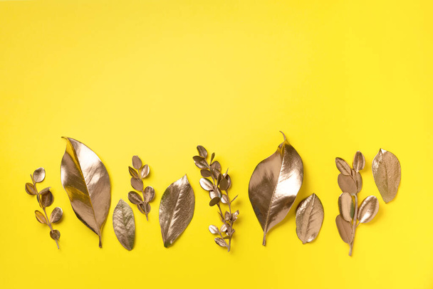 Golden leaves on yellow background. Top view. Copy space. Summer and autumn concept. Creative design elements for invitation, wedding cards, valentines day, greeting cards. - Фото, изображение