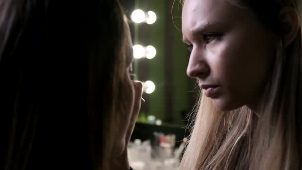atraktivní kavkazský make-up umělec dělá make-up pro mladé ženy v salonu krásy - Záběry, video