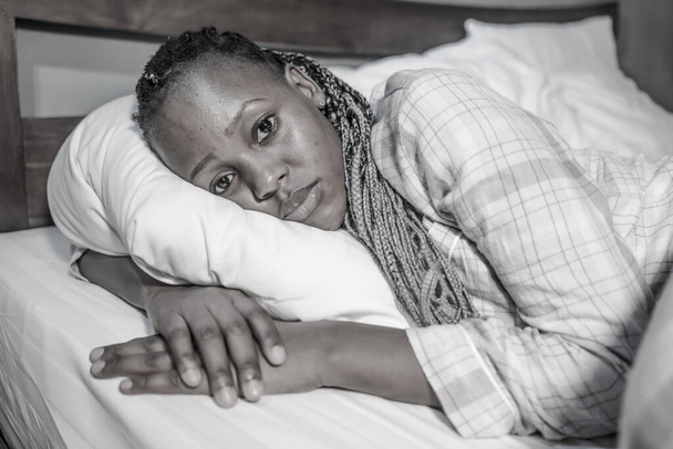 young African American girl at night suffering depression and insomnia - attractive sad and depressed black woman lying thoughtful and depressed on bed sleepless - Фото, изображение