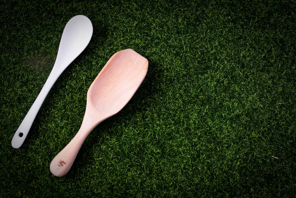 Ceramic spoon and wooden spoon on green background Copy space - Zdjęcie, obraz