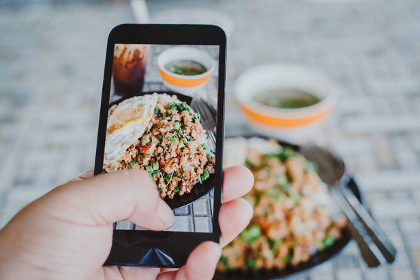 mão homem tirando foto comida tailandesa por telefone celular. Fotografia alimentar. Compartilhe fotografia de alimentos. Foto de comida popular - Foto, Imagem