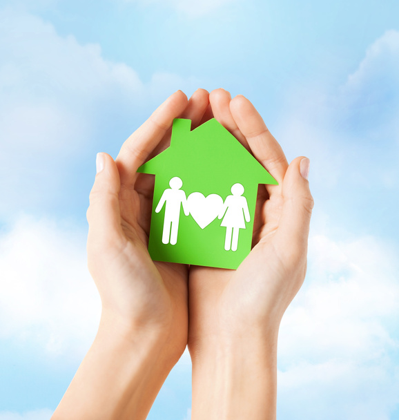 руки тримають зелений будинок з сім'єю
 - Фото, зображення