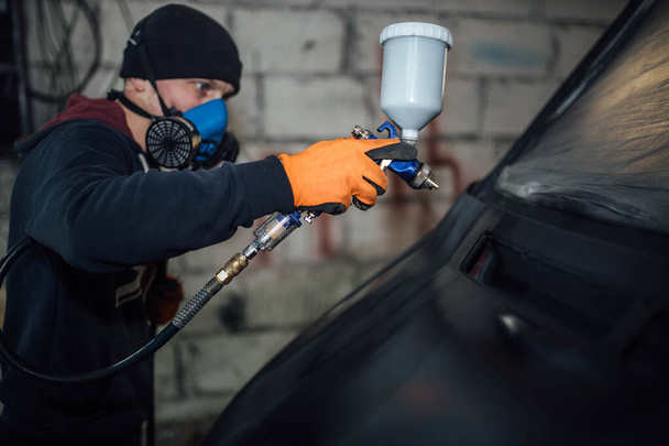 man paints a car, treatment of the body with epoxy primer. - Fotó, kép