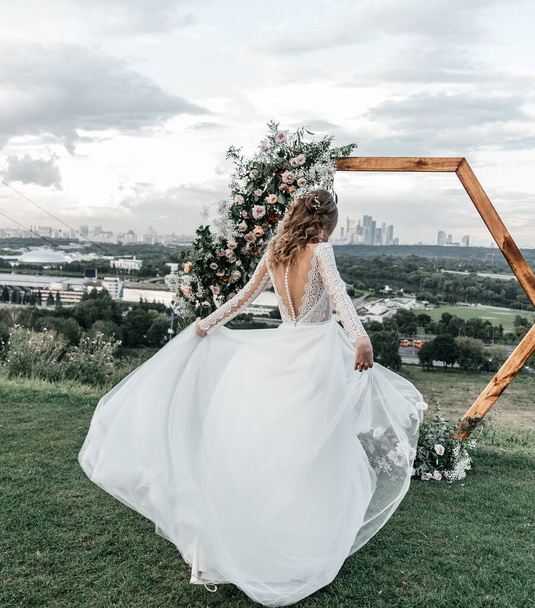 mooie mooie jonge slanke bruid in een luchtige elegante witte trouwjurk met kant glimlach zacht - Foto, afbeelding