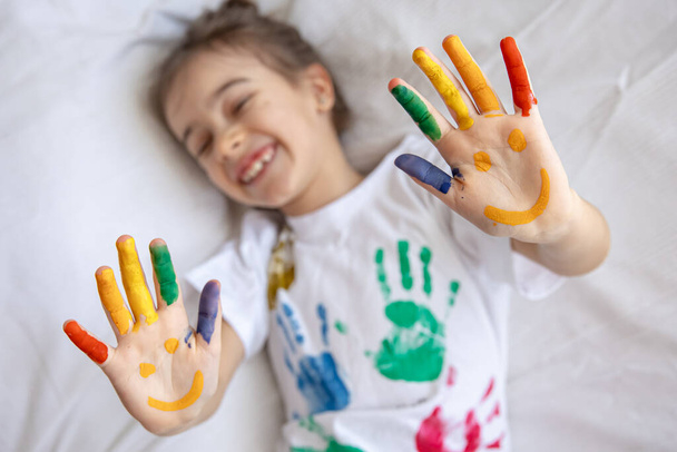 Sonrisas pintadas en las palmas de una niña. Dibujos brillantes divertidos en las palmas de los niños. - Foto, imagen