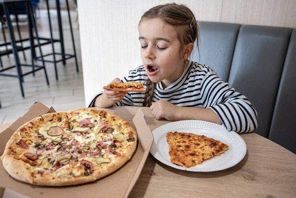 Zabawna dziewczynka jedząca pizzę w pudełku na lunch.. - Zdjęcie, obraz