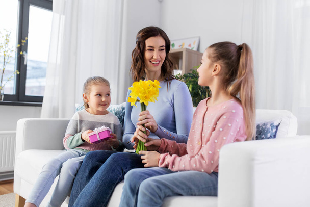 daughters giving flowers and gift to happy mother - Фото, изображение