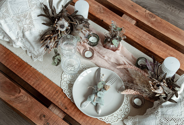 Ρομαντικό τραπέζι με κεριά και αποξηραμένα λουλούδια για ένα γάμο ή την ημέρα του Αγίου Βαλεντίνου. - Φωτογραφία, εικόνα