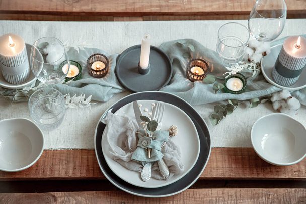 Detailaufnahme einer festlichen Tischdekoration mit Besteck, Teller und Kerzen im Kerzenständer. - Foto, Bild