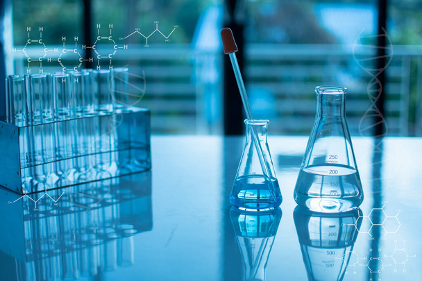 Concepto de experimento químico en laboratorio científico Dos frascos científicos de diferentes tamaños contienen diferentes sustancias químicas. Los productos químicos están en muchos tubos de vidrio que se colocan en la mesa y borrosa. - Foto, Imagen