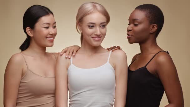 Internationale Freundschaft. Fröhliche asiatische, kaukasische und afrikanisch-amerikanische Damen lachen zusammen, beiger Studiohintergrund - Filmmaterial, Video