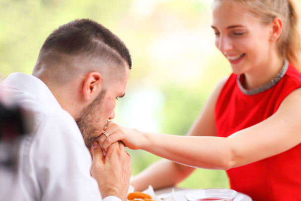 Uomo baciare la mano della sua ragazza dopo averle proposto la cena di lusso appuntamento nel giorno di San Valentino con superficiale attenzione selettiva sul suo occhio - Foto, immagini