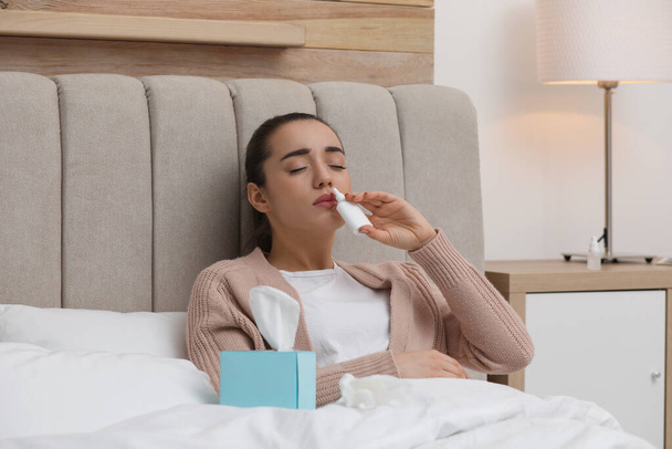Sick young woman using nasal spray in bed at home - Zdjęcie, obraz