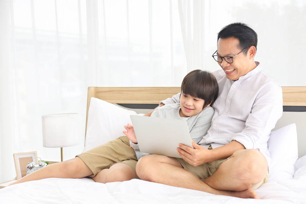 Asiatico padre teaching homework a suo figlio in letto per homeschooling e education concept - Foto, immagini