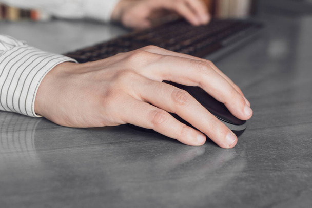 Femme d'affaires cliquant sur la souris et tapant sur le clavier au travail - Photo, image