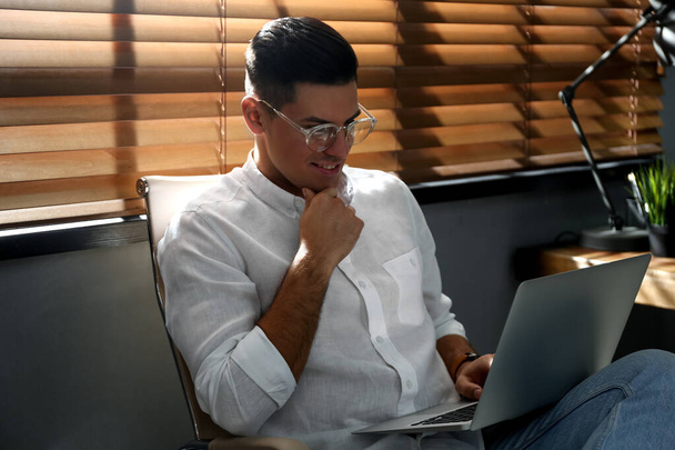 Freelancer working on laptop near window indoors - Φωτογραφία, εικόνα