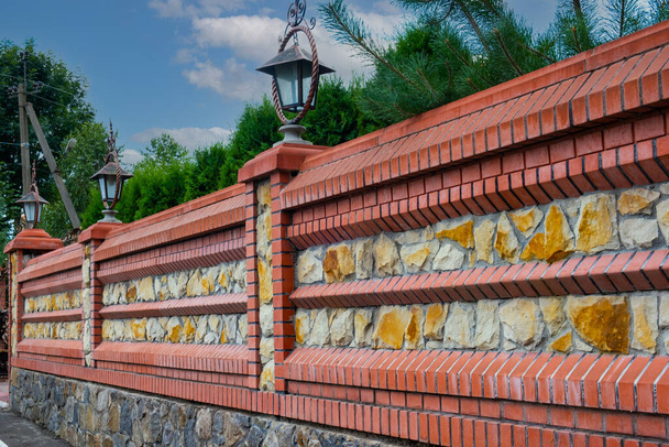 Cerca moderna decorativa feita de tijolo vermelho e branco com colunas de tijolo - Foto, Imagem