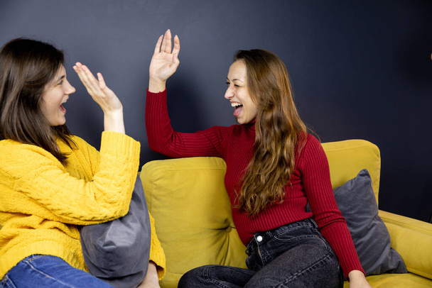 twee mooie meisjes gebaren high-fives lachen en kijken naar elkaar - Foto, afbeelding
