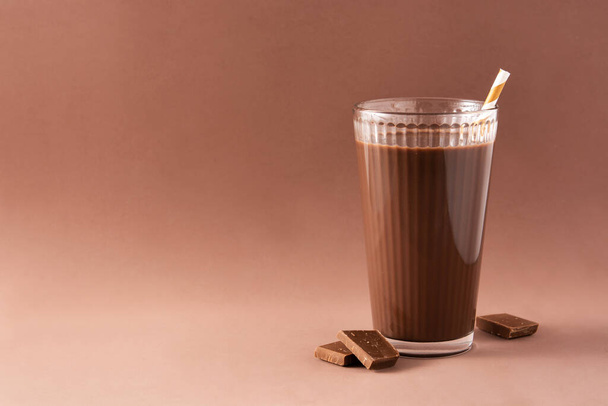 Chocolate milkshake in glass on brown background. Copy space - Фото, изображение