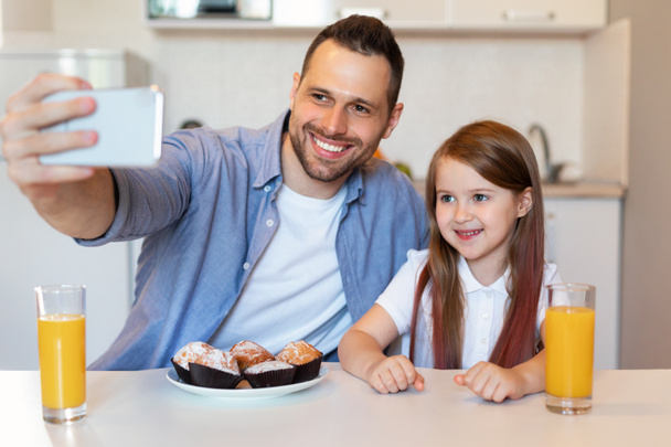 heureux papa et fille faire selfie avoir petit déjeuner dans cuisine - Photo, image