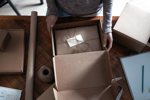 Top view of female business owner working, packing the order for shipping to customer - Foto, afbeelding