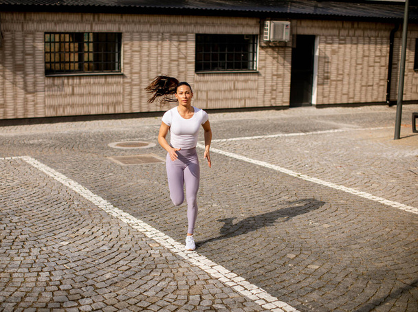 Красивая молодая женщина бежит по улице - Фото, изображение
