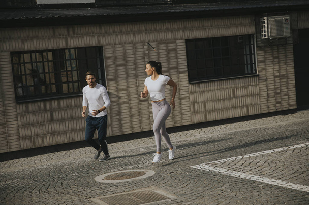Jóképű fiatal pár fut a városi környezetben - Fotó, kép