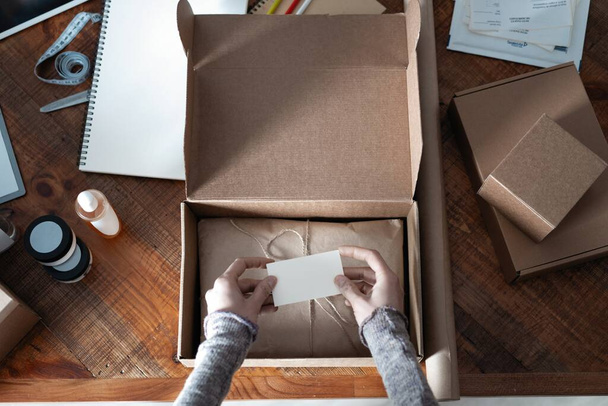 Top view of female business owner working, packing the order for shipping to customer - 写真・画像